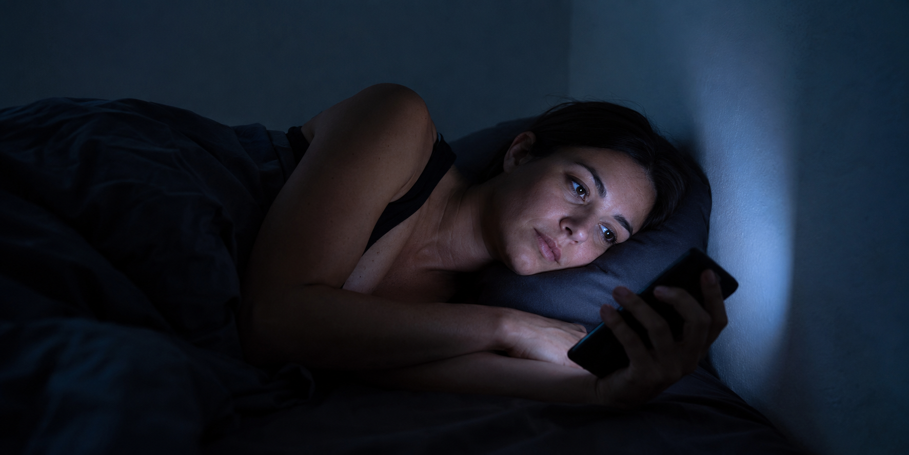 Phone and laptop on the bed at night